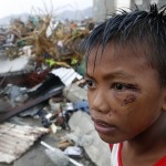 A boy who was wounded by flying debris due to Super Typhoon Haiyan stays at the ruins of his family’s house in Tacloban city